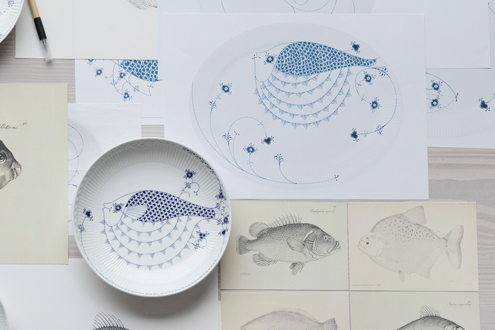A plate from the Royal Creatures lying on top of a lot of drawings of different fish